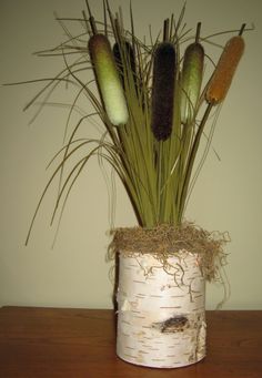 an arrangement of flowers in a white vase on a wooden table next to a wall