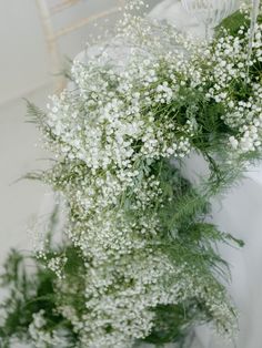 baby's breath flowers in a vase on a white tablecloth with a chair behind it