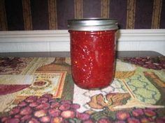 a jar filled with red liquid sitting on top of a table next to a wall