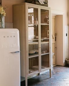 a white refrigerator freezer sitting inside of a kitchen next to a wooden cabinet with glass doors