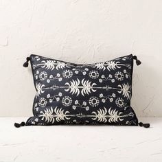 a black and white pillow with tassels on the front, sitting on a table