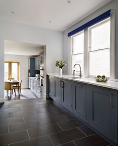 a kitchen with blue cabinets and white counter tops, along with a dining room table