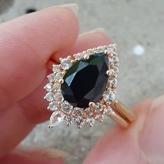 a close up of a person's hand holding a ring with a black diamond