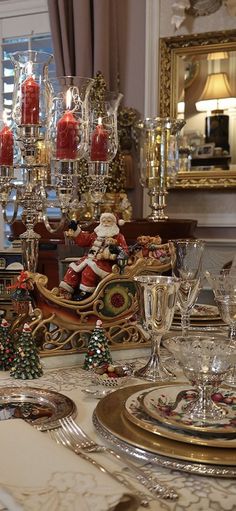 a dining room table set for christmas dinner with candles and decorations on it, along with santa's sleigh