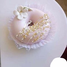 a pink donut decorated with white and gold sprinkles on a plate