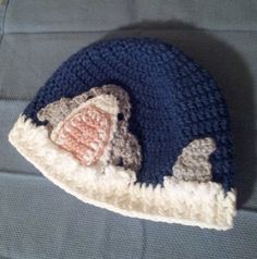 a crocheted hat with an elephant on it sitting on the floor next to a stuffed animal