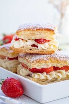 strawberry shortcakes are stacked on top of each other with powdered sugar and strawberries