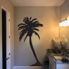 a bathroom with a palm tree decal on the wall next to a sink and mirror