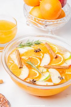 a bowl of oranges and apples with cinnamon stick garnish on the side