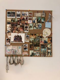 a cork board with pictures and magnets attached to the wall next to a phone