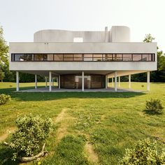 the building is made out of concrete and has large windows on each side, while grass surrounds it