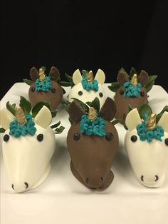 chocolate covered strawberries decorated like unicorns with blue bows and green leaves on them