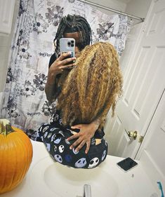 a woman with dreadlocks taking a selfie in front of a bathroom mirror