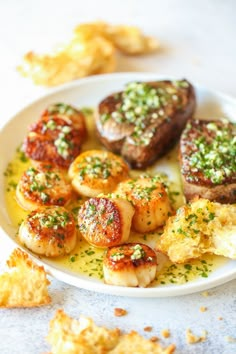 a white plate topped with scallops and potatoes