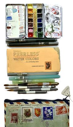 an assortment of watercolors and pencils in tins on top of each other