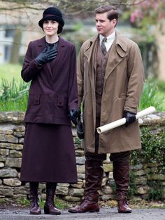 a man and woman dressed in period clothing standing next to each other on the street