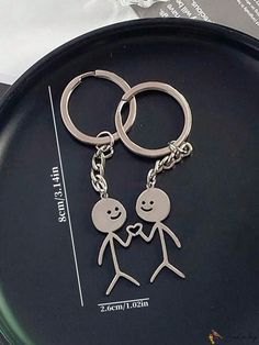 two people holding hands on a black plate with silver keychains and an envelope in the background