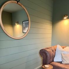 a living room with a brown couch and round mirror on the wall next to it