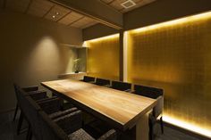 an empty conference room with wooden tables and chairs in front of a large gold wall