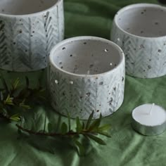 three white candles sitting on top of a green cloth