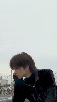 a young man sitting on top of a wooden bench