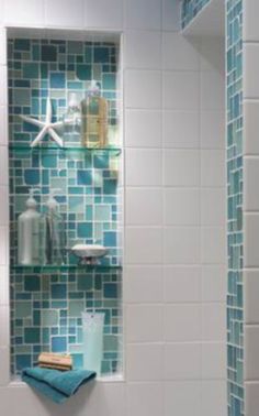 a bathroom with blue and white tiles on the walls, shower head and shelf in the corner