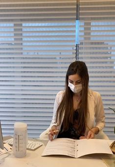 a woman wearing a face mask while sitting at a desk