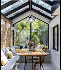 a room with a table, couches and windows in the ceiling is lit by an outdoor light