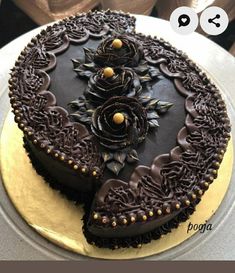 there is a chocolate cake with gold decorations on the top and bottom, sitting on a plate