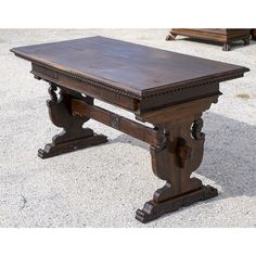 an old wooden table sitting on top of a cement floor next to other wood furniture