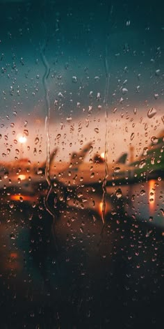 rain drops on the window as an airplane sits in the background