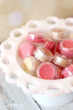 a white bowl filled with pink and yellow lip glosses