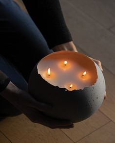 a person holding a bowl with candles in it