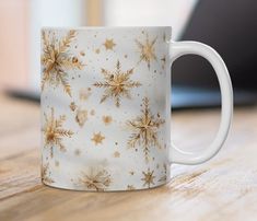 a white coffee mug with gold snowflakes on it