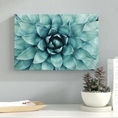 a blue flower on a white table next to books and a plant in a vase