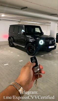 a hand holding a cell phone in front of a black jeep parked in a parking garage