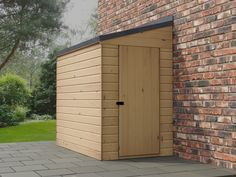 a wooden storage shed next to a brick wall