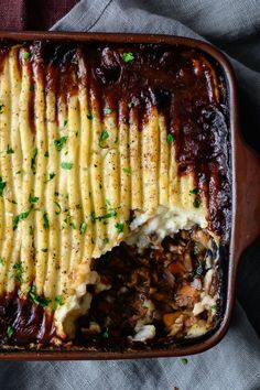 a casserole dish with meat, potatoes and gravy in it on a cloth