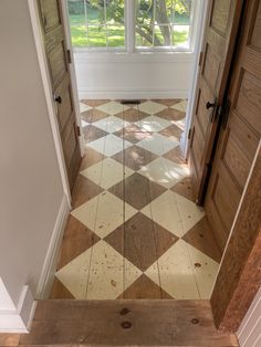 an open door leading into a room with checkered tile flooring and wooden doors