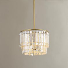 a chandelier hanging from the ceiling with white and gold circles on it's sides