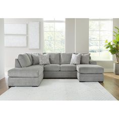 a living room with a large gray sectional couch and white rugs on the floor