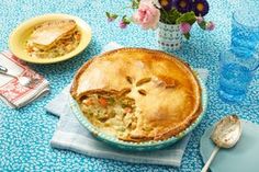 a pie sitting on top of a blue table cloth next to a bowl of food