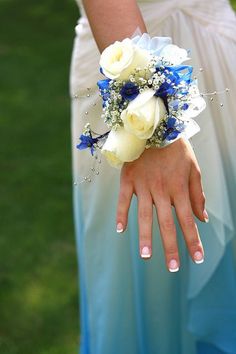 a woman in a blue dress holding a bouquet of white and blue flowers on her hand