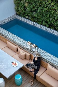 a woman sitting on a couch next to a swimming pool