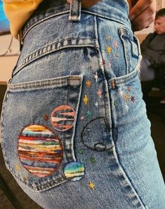 a woman is showing off her jeans with patches on them