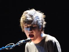 a young man singing into a microphone on stage