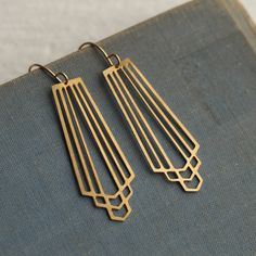 These great earrings are made with solid brass and feature a graduated art deco design.  They remind us of classic Deco architecture, like the Chrysler building!   The earrings measure 45mm (just under two inches) in length and have gold plated ear wires.   They have been designed and made in our Edinburgh studio.   This piece of handmade jewellery comes packaged in a nice recycled gift box with a handmade tag, all ready to give or keep. We also have these earrings in silver, as well as  many other Art Deco designs!  🖤 FASTER SHIPPING 🖤 Need this fast? We offer a Faster Shipping option here: https://www.etsy.com/uk/listing/100107311/faster-shipping-priority-post-upgrade 🖤 GIFT MESSAGE & WRAP SERVICE! 🖤 https://www.etsy.com/uk/listing/750160511/gift-wrap-wrapping-personalised-card?ref=l Retro Brass Jewelry With Matching Earrings, Art Deco Dangle Brass Earrings, Art Deco Brass Jewelry With Matching Earrings, Retro Brass Drop Earrings, Retro Brass Dangle Jewelry, Nickel-free Art Deco Metal Earrings, Handmade Brass Art Deco Earrings, Retro Brass Earrings, Gold Brass Art Deco Earrings