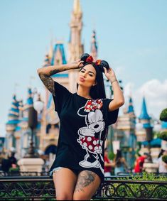 a woman posing for a photo in front of a castle with her hand on her head