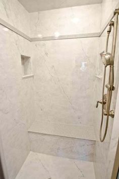 a walk in shower sitting next to a white tiled wall and floor covered in marble