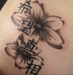 the back of a woman's shoulder with flowers and chinese characters on it,